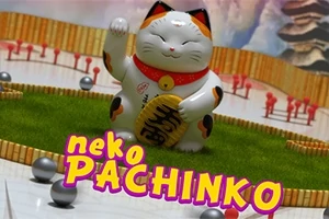 Egy fehér maneki-neko macska figura piros nyaklánccal és arany táblával, zöld gyepen ül, körülötte kis fémgolyók és fa kerítés, alul pedig a neko PACHINKO felirat látható