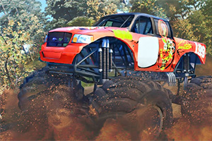 Piros és narancssárga színű monster truck nagy kerekekkel, amint egy poros és erdős terepen halad